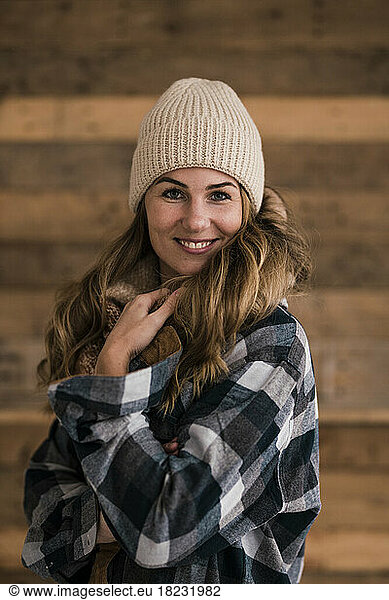 Beautiful smiling woman wearing knit hat standing in front of wall