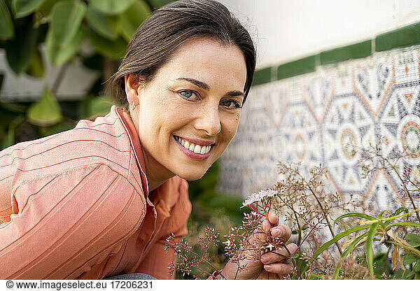 Beautiful smiling woman with blue eyes holding flowers in garden