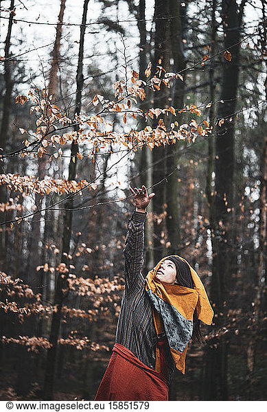 beautiful strong asian woman dancer reaches for gold leaf in autumn