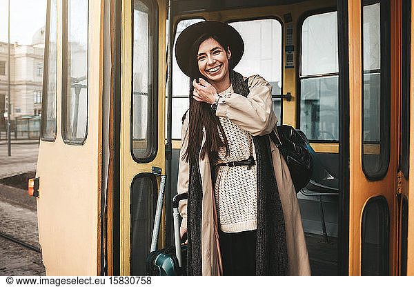 Beautiful stylish girl traveler with suitcase gets off the tram