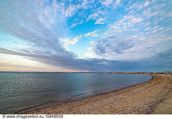 Beautiful sunset sky colors and clouds above the beach shoreline.