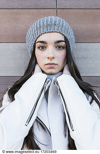 Beautiful teenage girl in knit hat against wall