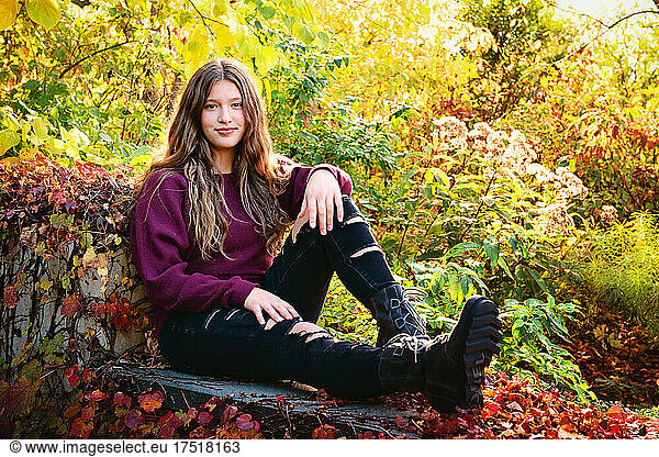 Beautiful tween girl with long hair sitting outdoors in fall colors.