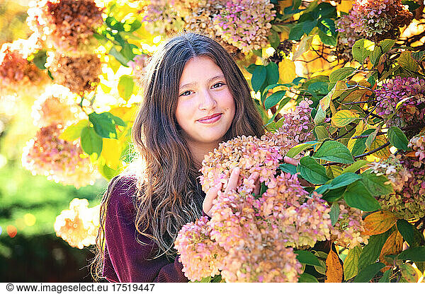 Beautiful tween girl with long hair standing by flowering tree.