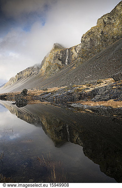 Beautiful view of mountains reflecting by sea against cloudy sky at Hvalnes Nature Reserve Beach  Iceland