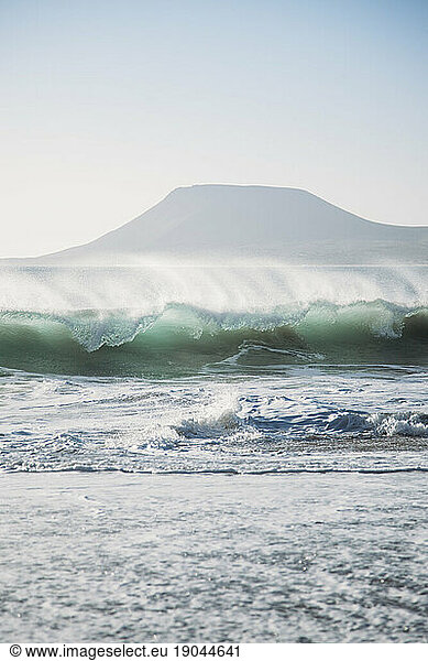 Beautiful wave breaking with a mountain behind.