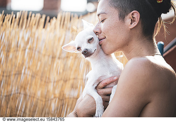 beautiful woman and tiny dog smile and embrace in afternoon sun