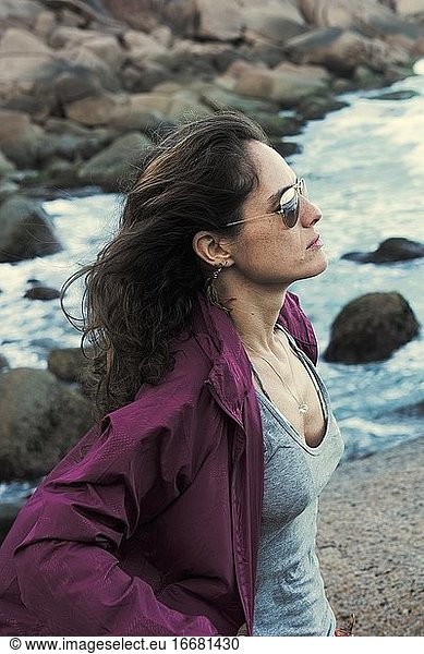 Beautiful woman contemplating the ocean with purple rain coat
