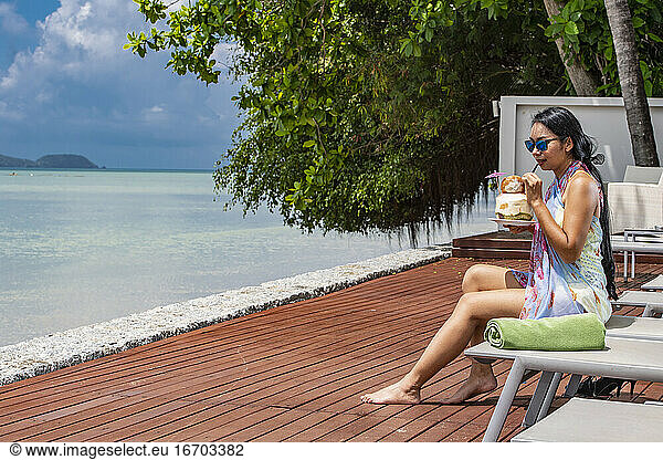 beautiful woman drinking coconut juice at luxury resort in Phuket