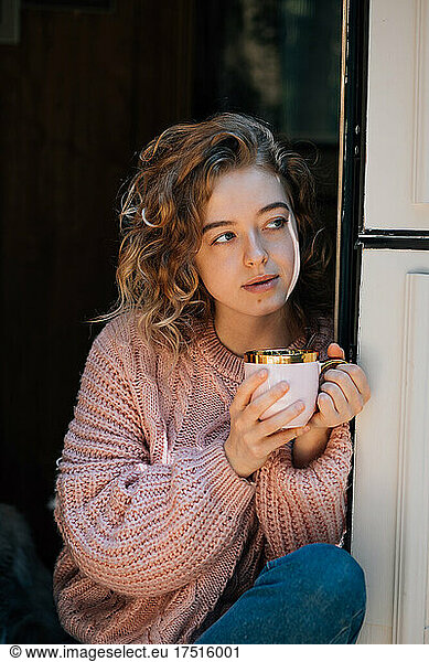Beautiful woman drinking coffee in door of trailer.