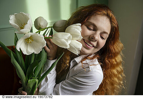 Beautiful woman holding bunch of tulip flowers at home