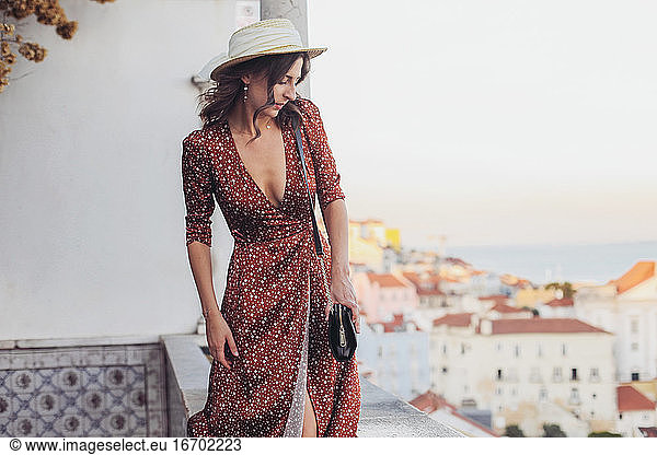 Beautiful woman in dress and hat walking on a view point of Lisbon