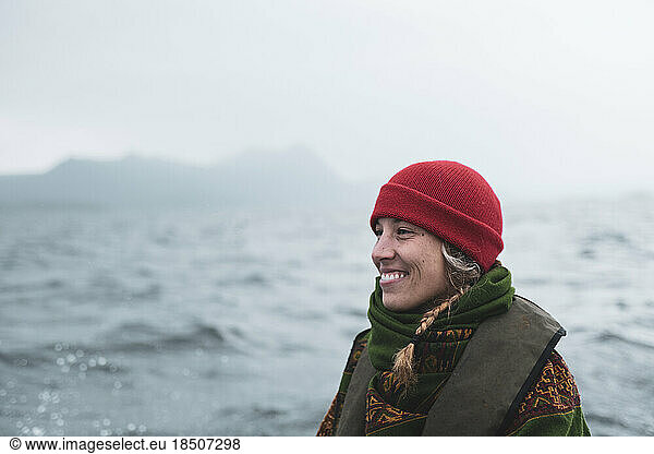 Beautiful woman in red hat smiles on edge of boat through islands