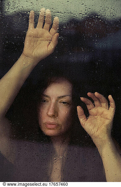 beautiful woman look through wet glass