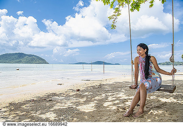 beautiful woman sitting on a swing at the beach in Phuket