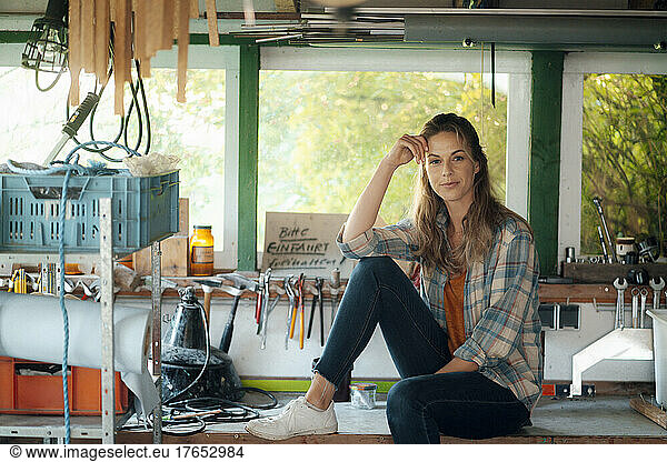 Beautiful woman sitting on table in garage