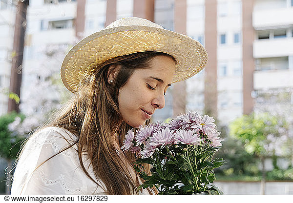 Beautiful woman smelling bouquet of fresh pink flowers at springtime