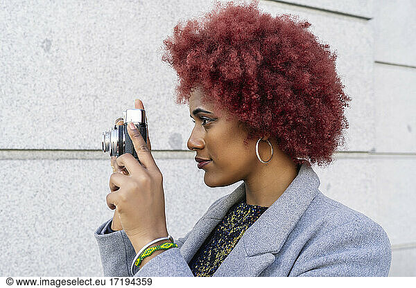 beautiful woman with afro hair taking pictures with her old camera