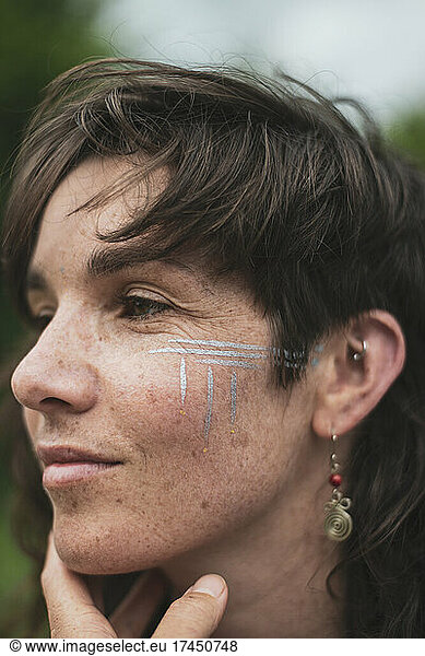 Beautiful woman with brown hair  freckles  silver tribal facepaint