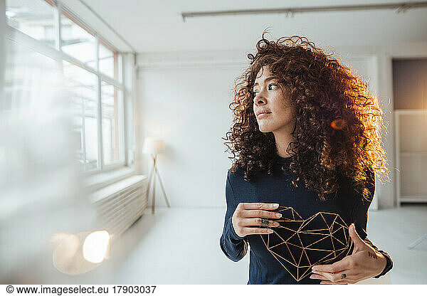Beautiful woman with curly hair holding heart shape model