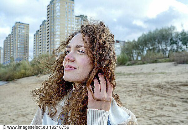Beautiful woman with curly hair in front of buildings at beach