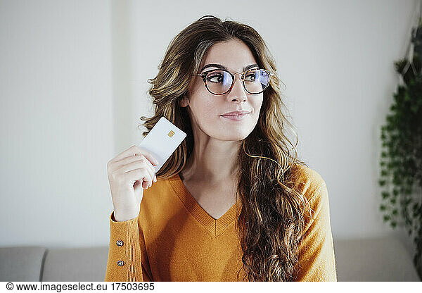 Beautiful woman with eyeglasses holding credit card at home
