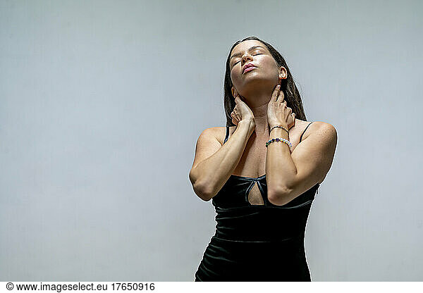 Beautiful woman with eyes closed touching her neck