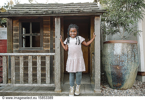 Beautiful young black girl with long braids on porch of small cabin