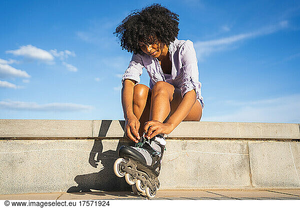 Beautiful young black woman putting on inline skates