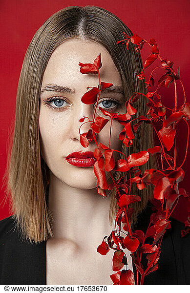 Beautiful young blond woman with red twig