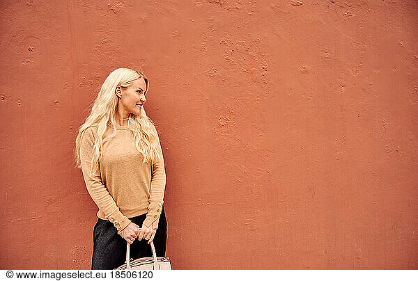 Beautiful young female by orange wall