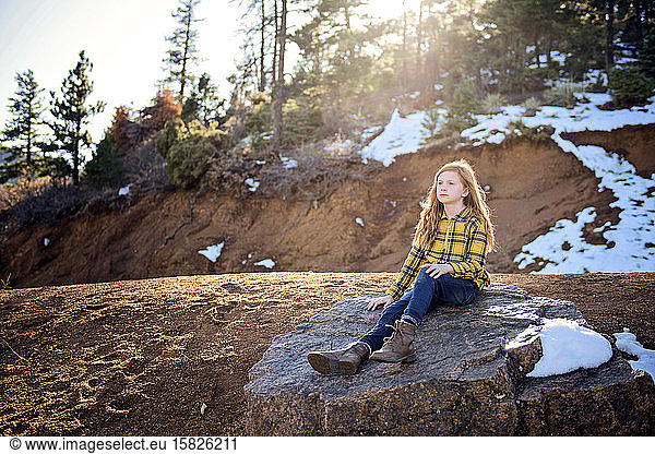 Beautiful Young Girl Sitting on Rock in the Sunshine on Mountain Path