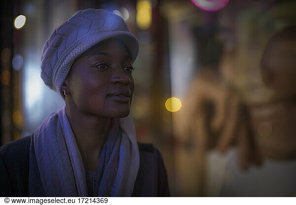 Beautiful young woman in hat and scarf at night