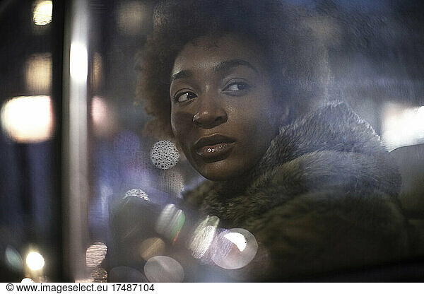 Beautiful young woman looking out car window at night