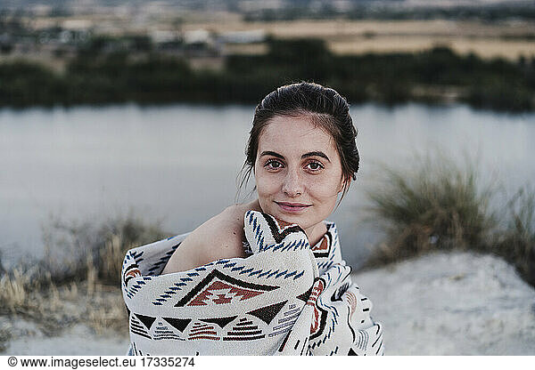 Beautiful young woman wrapped in blanket at sunset