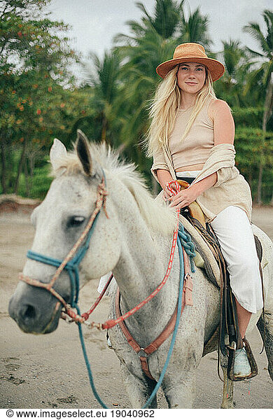 beauty blond girl riding horse at the beach in Costa Rica