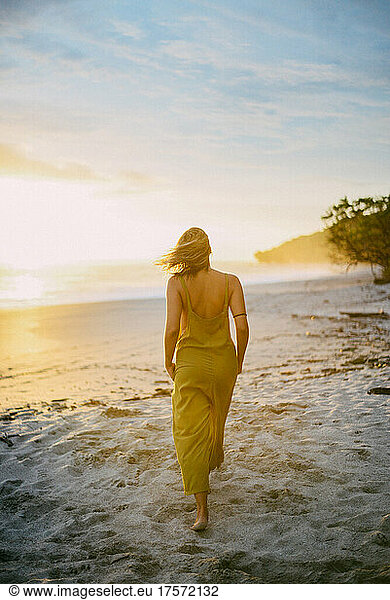 beauty blond girl walking on the beach during the sunset