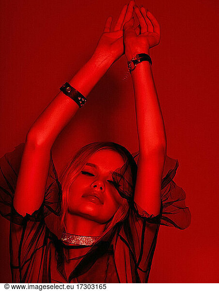 Beauty fashion portrait with red lighting filter. Beauty girl face close up. Closeup blonde woman with dark liner eyes and black hat having fun, good mood, dancing, relaxing. neon light red c