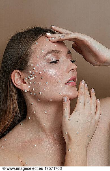 Beauty portrait of a girl with natural makeup and pearls on her face
