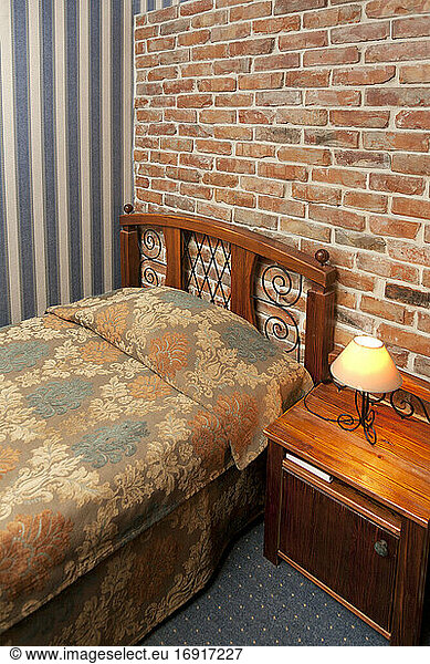 Bed in bedroom with wallpaper and brick wall.