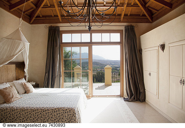 Bed with canopy and French doors leading to balcony in bedroom