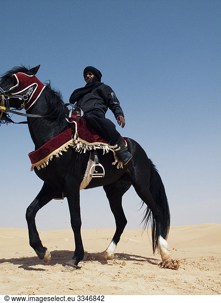 Bedouin on a black horse against a blue sky  Tunisia.