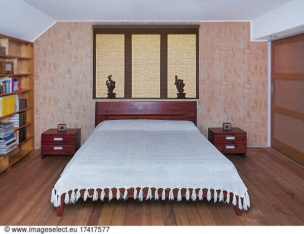 Bedroom interior with large bed  furniture and bedside table  shadows on roller blind.