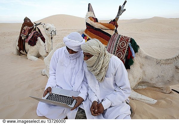 Beduinen benutzen einen Laptop in der Sahara.