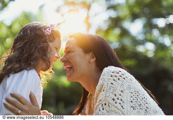 Begeisterte Mutter und Tochter lächeln von Angesicht zu Angesicht