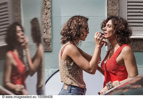 Behind the scenes of an urban fashion shoot with make up artist applying lipstick to model