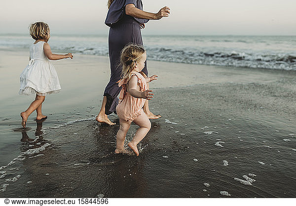 Behind view of young family walking towards the ocean at sunset, Behind view of young family walking towards the ocean at sunset