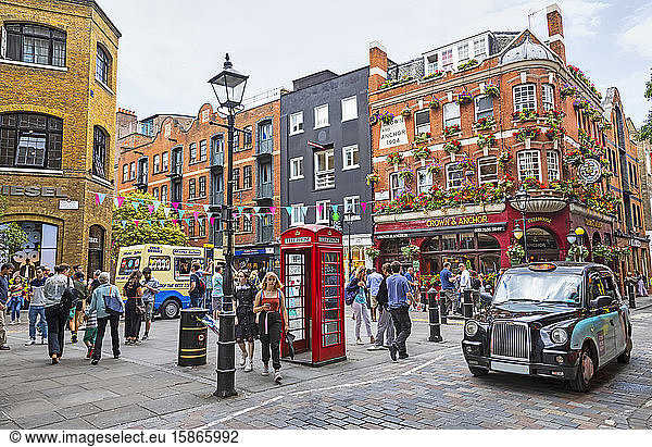 Belebte Straßenszene und Stadtleben an einer Straßenecke mit roter Telefonzelle; London  England