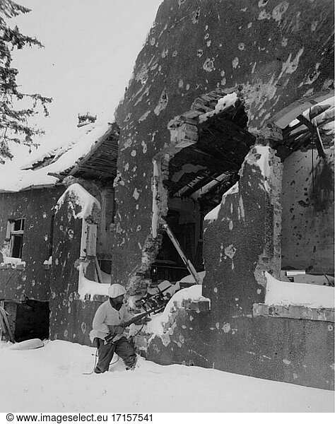 BELGIEN Muringen -- 30. Januar 1945 -- US Army Pfc DC Cox von Company M  26th Infantry  1st Division  FUSA  auf der Suche nach deutschen Scharfschützen in den Ruinen einer belgischen Stadt in der Nähe von Muringen  während eines großen deutschen Gegenangriffs  der später als Ardennenoffensive bekannt wurde -- Bild von Bill Augustine / Lightroom Photos / US Army *Beste verfügbare Qualität. Nicht auf Staub oder Kratzer retuschiert.