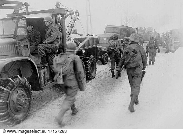 BELGIEN Murringen -- 31. Januar 1945 -- Truppen des 3. Bataillons  26. Infanterieregiment  1. Infanteriedivision  Erste US-Armee  bewegen sich während eines großen deutschen Gegenangriffs  der später als Ardennenoffensive bekannt wurde  an gesäumten Fahrzeugen vorbei in die Stadt Murringen  Belgien -- Bild von Murray Shub / Lightroom Photos / US Army *Beste verfügbare Qualität. Nicht auf Staub oder Kratzer retuschiert.